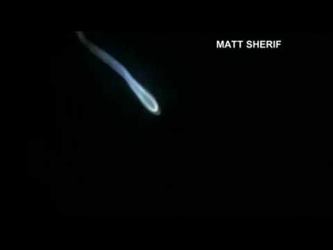 Smoke trail left by rocket launch lights up night sky