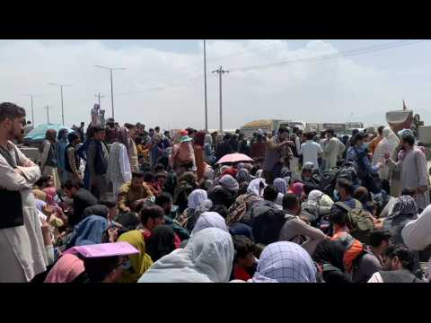Afghans wait in the open near Kabul airport in hope to flee country