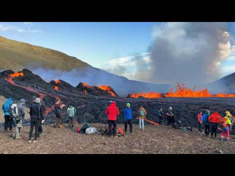 People watch as lava spews out of volcanic fissure in Iceland