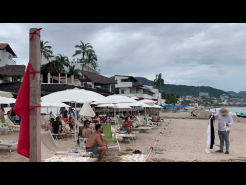 Mexicans enjoy the beach as gray skies of tropical storm Lidia loom in distance