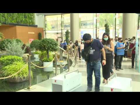 People queue to enter Siam Paragon mall as shopping centres reopen in Thailand