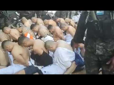 Honduras military police guard handcuffed inmates in prison