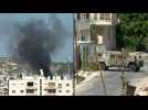 Smoke rises from building as Israeli army vehicles patrol Jenin